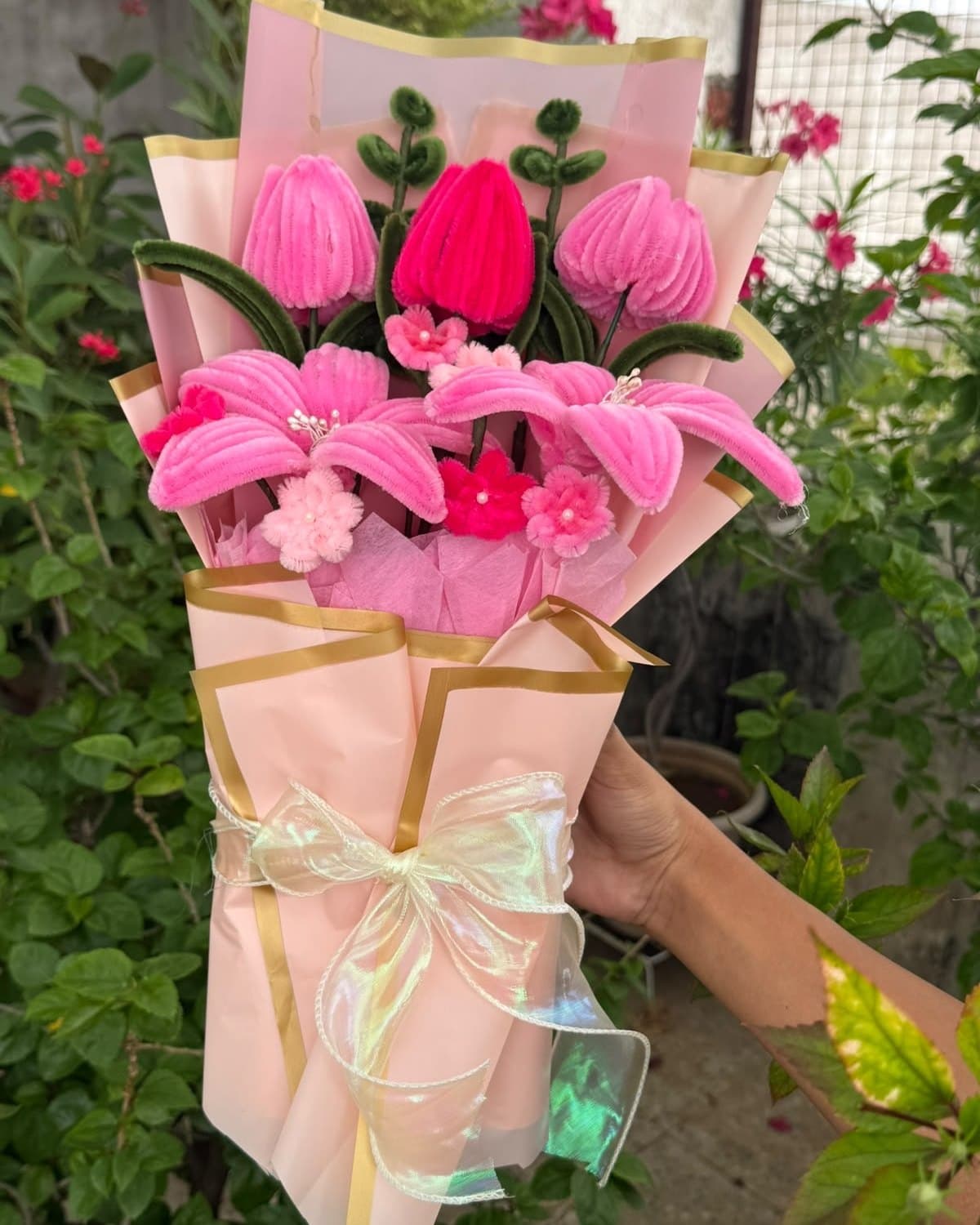 Pipe cleaner bouquet of pink tulips, pink lilies and small blossoms in blush paper with a gold edge