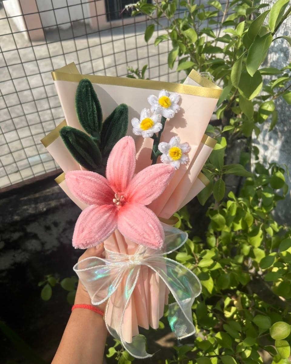 Pipe cleaner bouquet of a pink lily and three white daisies in blush paper with a gold edge